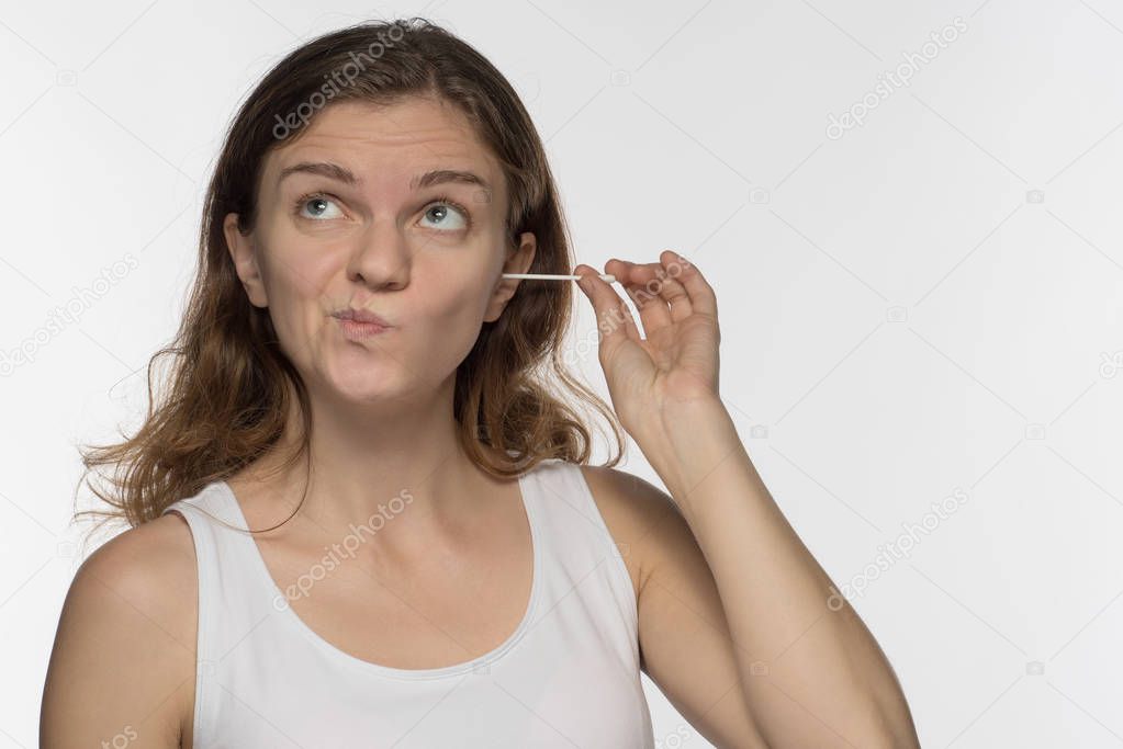 Young beautiful brunette girl cleans the ears with chopsticks wi