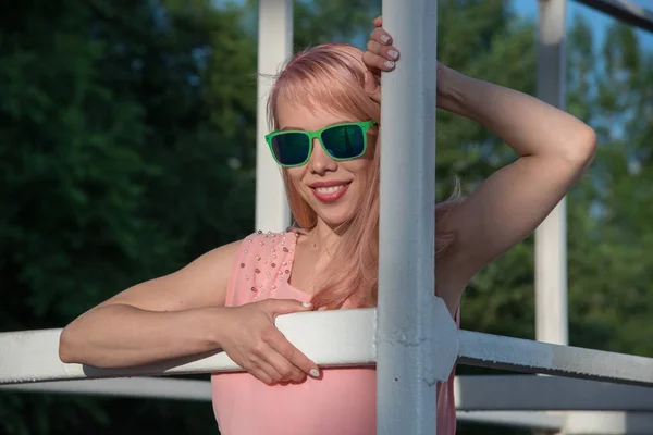 Piękna dziewczyna w okularach słonecznych i różowa sukienka pozowanie na lato — Zdjęcie stockowe