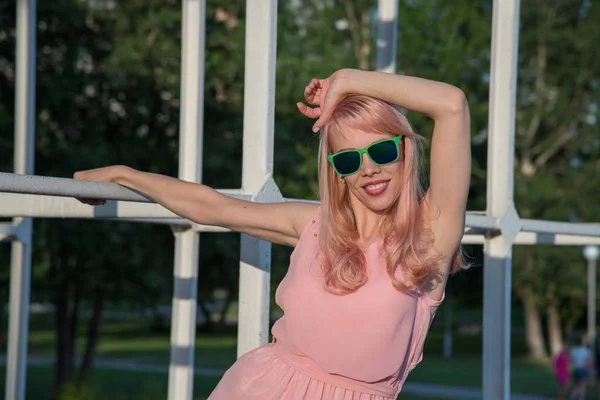 Menina bonita em óculos de sol e vestido rosa posando para um verão — Fotografia de Stock