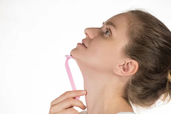 Young beautiful woman shaves a chin with a razor on a white back — Stock Photo, Image