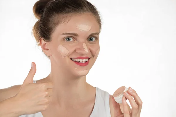 Young brunette woman applying makeup on skin foundation and smil — Stock Photo, Image