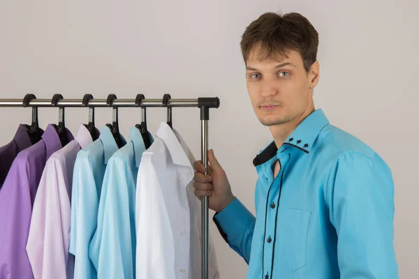 Jonge sexy man kiest een shirt uit een verscheidenheid van shirts opknoping — Stockfoto