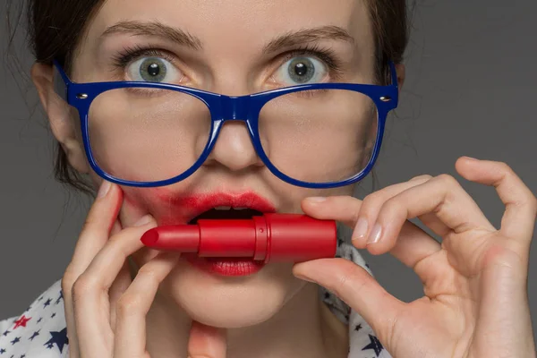 Mooie jonge brunette meisje in glazen met rode lippenstift op li — Stockfoto