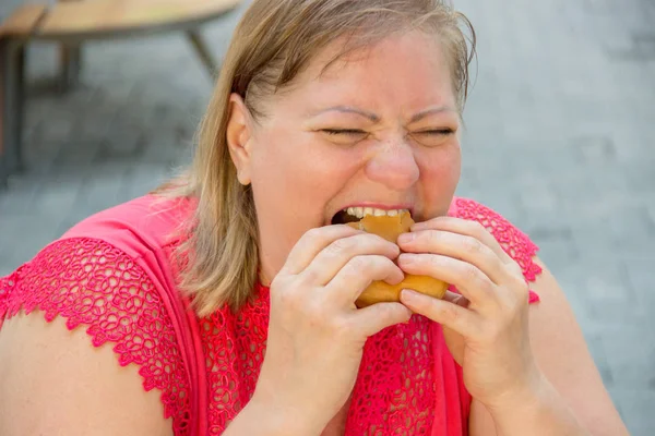 Silná žena jíst fast food hamburger a hranolky v kavárně — Stock fotografie