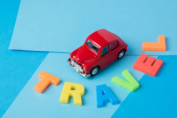 Carro de brinquedo vermelho e cartas de viagem de plástico inscrição em um bac azul — Fotografia de Stock
