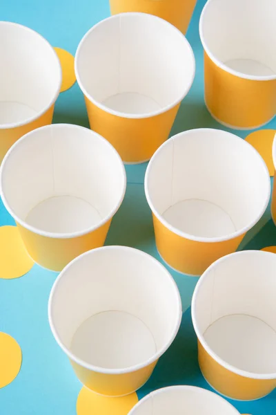Tazas de papel amarillo para una fiesta sobre fondo azul — Foto de Stock