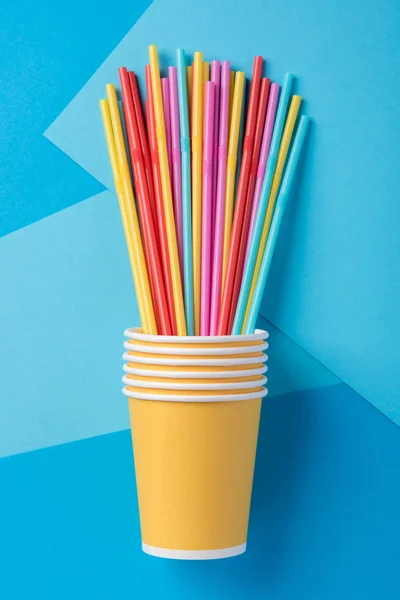 Yellow, blue, pink and red straws for a party in paper cups on a
