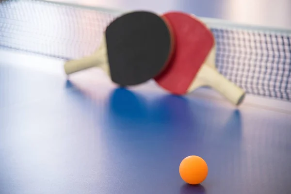 Orange ball for table tennis and two rackets of red and black co