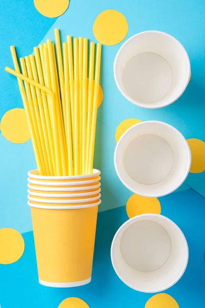 Pajitas amarillas para una fiesta en vasos de papel sobre un fondo brillante — Foto de Stock