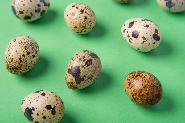 Красиві плямисті свіжі перепелині яйця на зеленому паперовому фоні — стокове фото