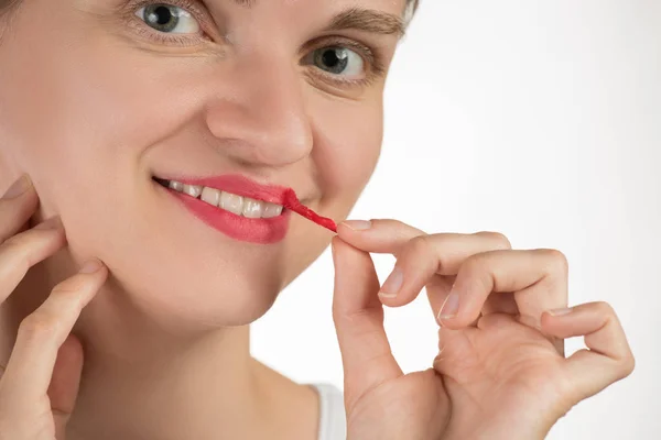 Una hermosa joven aplica un lápiz labial rojo líquido persistente — Foto de Stock