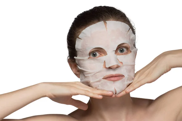 Beautiful young woman is applying a cosmetic mask on a face on a — Stock Photo, Image