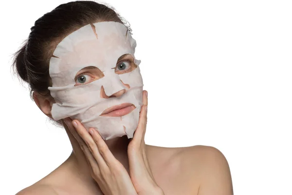 Hermosa joven está aplicando una máscara cosmética en una cara en un — Foto de Stock