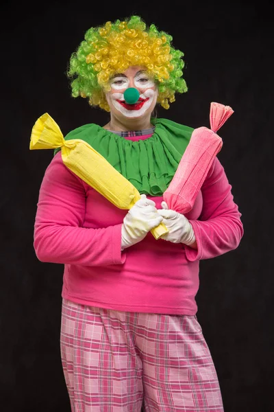 Funny clown with hair and a cheerful make-up holding a gift — Stock Photo, Image