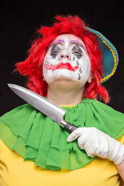 Scary clown with a horrible make-up laughs and with knives in ha — Stock Photo, Image