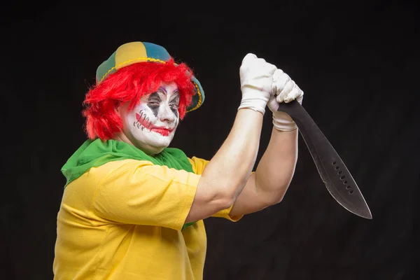 Scary clown with a horrible make-up laughs and with knives in ha — Stock Photo, Image