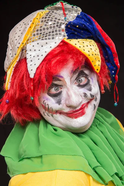 Een afschuwelijk clown met een verschrikkelijke make-up en hoed lachen op een b — Stockfoto