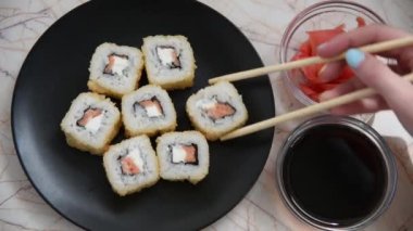 İnsanlar Japon yemek yemek. Lezzetli rulo ahşap sopa ile alınır ve soya sosuna batırılmış