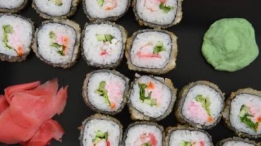 Japon yemekleri. Pişmiş rulo, wasabi ve siyah bir plaka üzerinde pembe zencefil