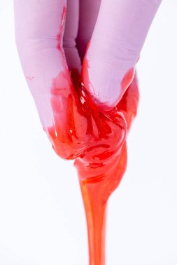 Bir eldiven kadın eli depilat için kırmızı şeker hamuru veya balmumu tutar