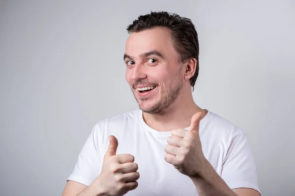 Hombre guapo con cerdas en camiseta blanca sonriendo y sostiene una —  Fotos de Stock