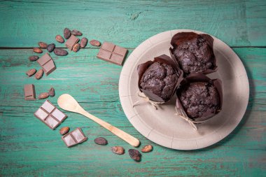 Fresh baked muffins, chocolate slices, cocoa beans and a spoon o