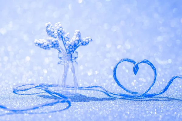 Blue thread in the shape of love of heart and a vase of flowers — Stock Photo, Image