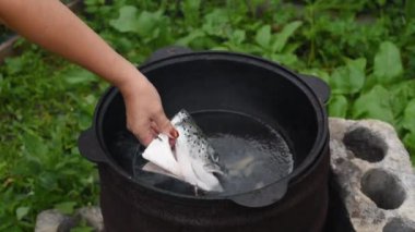 Yazın, bir şenlik ateşinde siyah bir kazanda somon kafasından balık çorbası pişirme süreci.