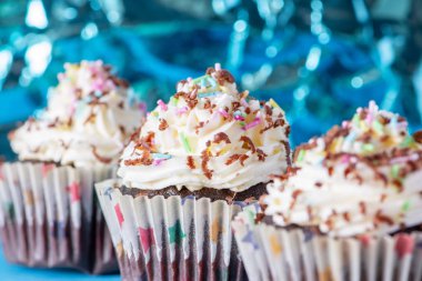 Delicious homemade cupcakes on a blue crumpled foil background. 