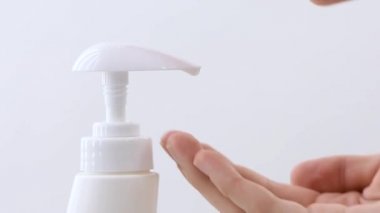 Beyaz bir arka planda ellerini yıkamak için sıvı şeffaf sabunla bir şeker kutusuna bastıran kadın ellerini kapat.