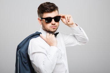 Young man in sunglasses holding jacket