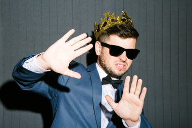 Young man in crown closing from everyone