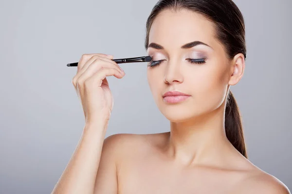 Chica pintando párpados con sombras de ojos — Foto de Stock