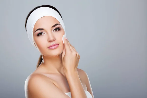 Model touching face with cotton pad