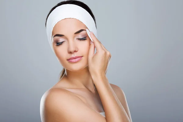 Woman touching face with cotton pad