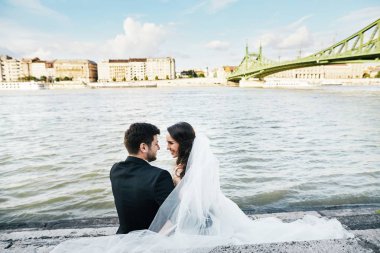 Gelin ve damat birlikte nehir kenarında oturan