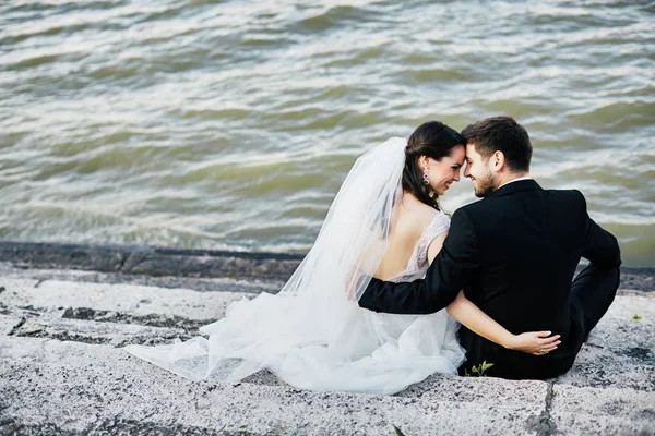 Bruid en bruidegom samen zitten in de buurt van rivier — Stockfoto