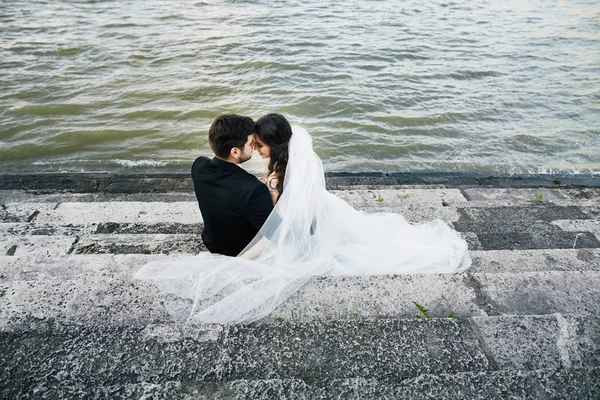 Наречена і наречений сидять разом біля річки — стокове фото