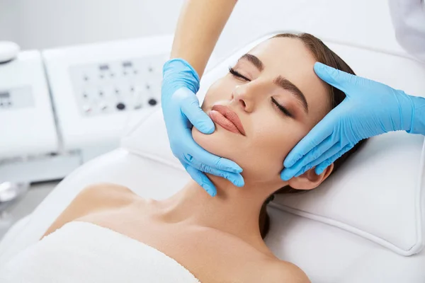 Doctor massaging face of beautiful woman — Stock Photo, Image