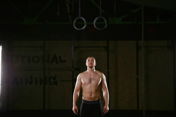 Спортсмен, стоящий под гимнастическими кольцами — стоковое фото