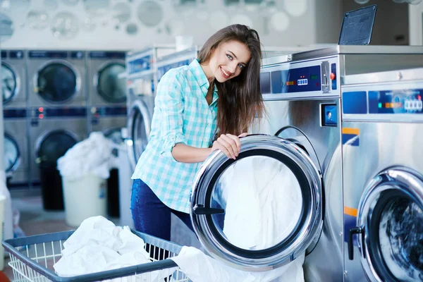 Женщина стоит рядом со стиральной машиной — стоковое фото