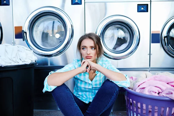 Женщина сидит рядом со стиральными машинами — стоковое фото