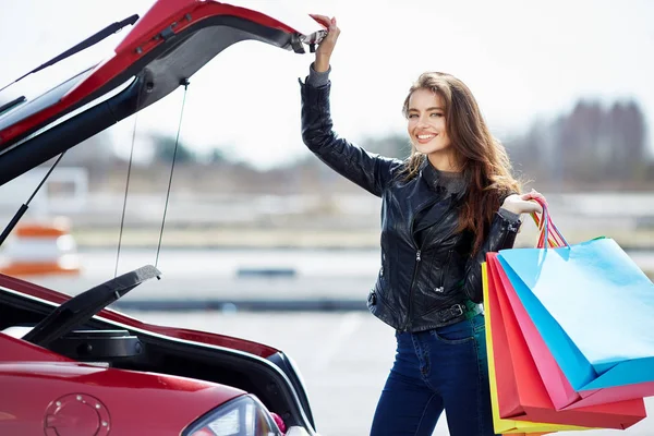 Žena uvedení barevné tašky do auta — Stock fotografie