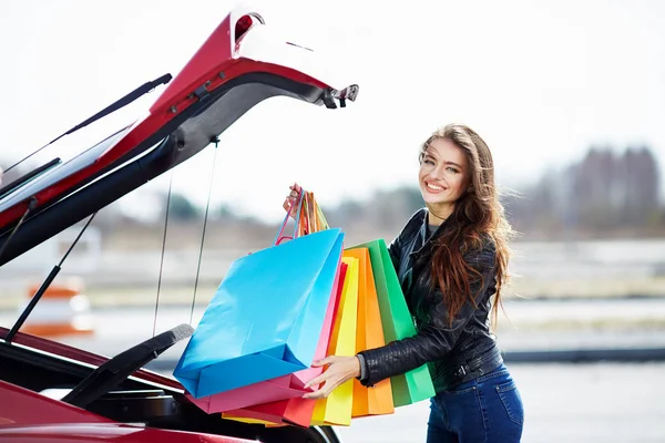 Žena uvedení barevné tašky do auta — Stock fotografie