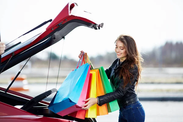 Woman putting colorful bags into car Stock Photo