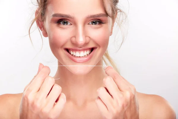 Chica sosteniendo los dientes hilo — Foto de Stock