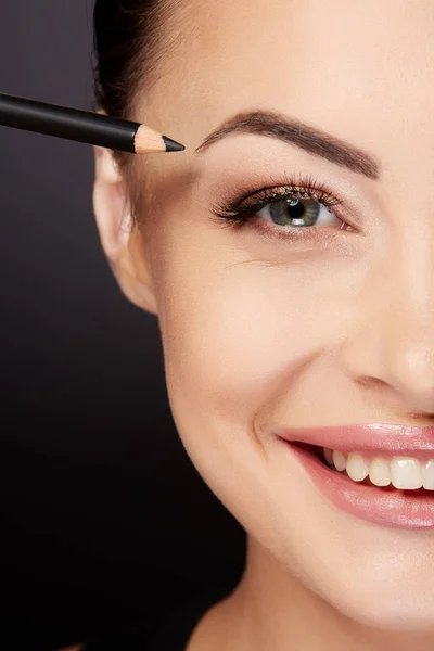 Mujer sonriente pintando cejas con lápiz negro — Foto de Stock