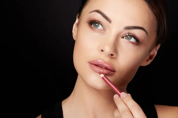 Model painting lips with red pencil