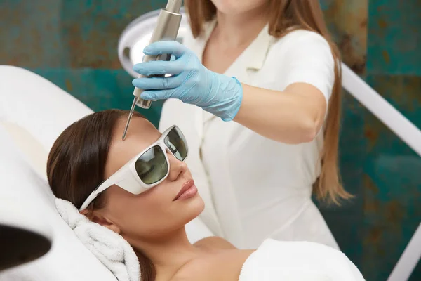 Attraente femmina che ha il trattamento facciale con laser nel salone di bellezza da cosmetologo professionista — Foto Stock