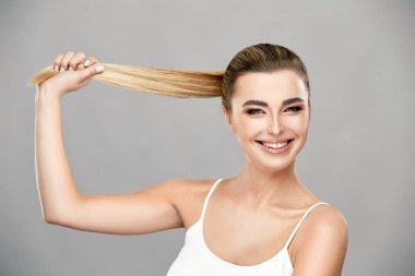 Beyaz tişörtlü, kameraya gülümseyen açık renk saçlı tatlı bir kız.